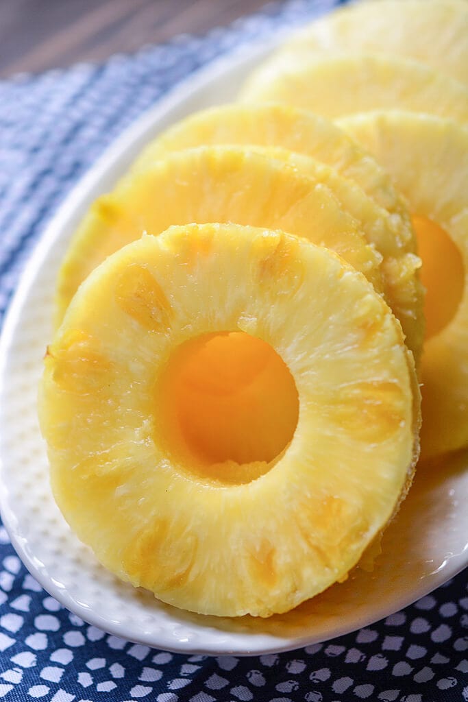 Sliced pineapple on a white plate with a blue napkin