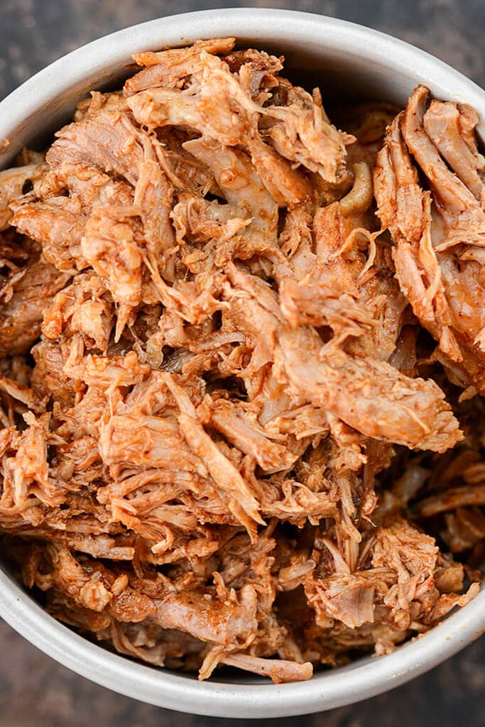 Gray bowl filled with shredded seasoned cooked Mexican style pork.