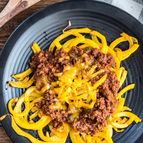 Overhead shot of Easy Skillet Cincinnati 'Skyline' Chili with Butternut Squash Noodles on a black plate with a white and gray checked napkin