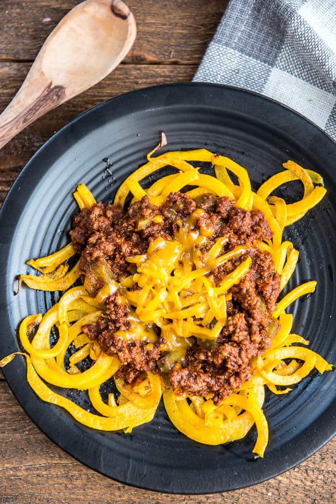 Overhead shot of Easy Skillet Cincinnati 'Skyline' Chili with Butternut Squash Noodles on a black plate with a white and gray checked napkin