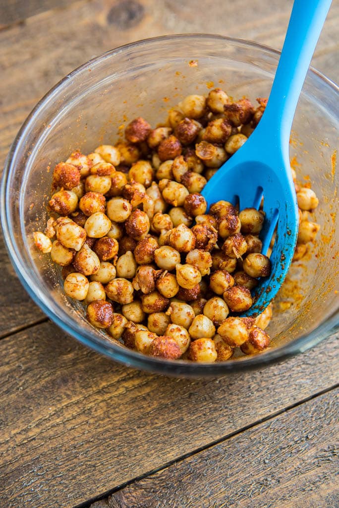 Chickpeas tossed with seasonings in bowl getting ready to bake for Crispy Chickpea Tostadas