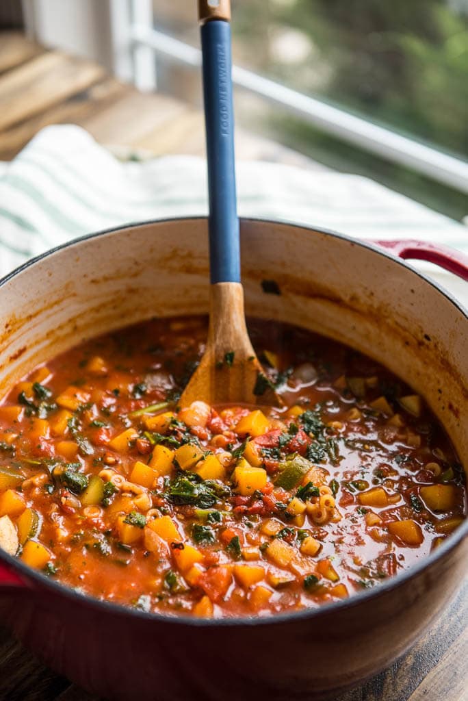 Butternut Squash Minestrone on table by window in a red dutch oven.