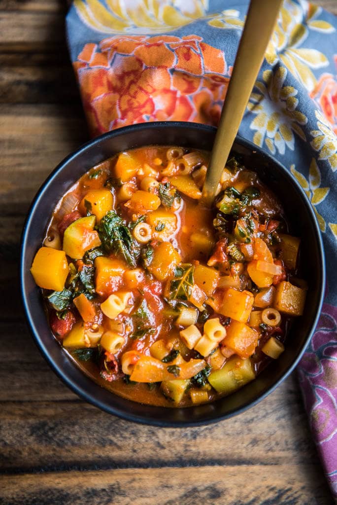 Overhead view of Butternut Squash Minestrone in a black bowl with a fall themed napkin