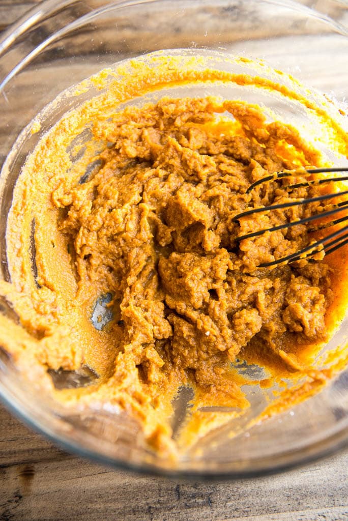 Canned pumpkin mixed with sugar for Mini Pumpkin pie filling in mixing bowl.