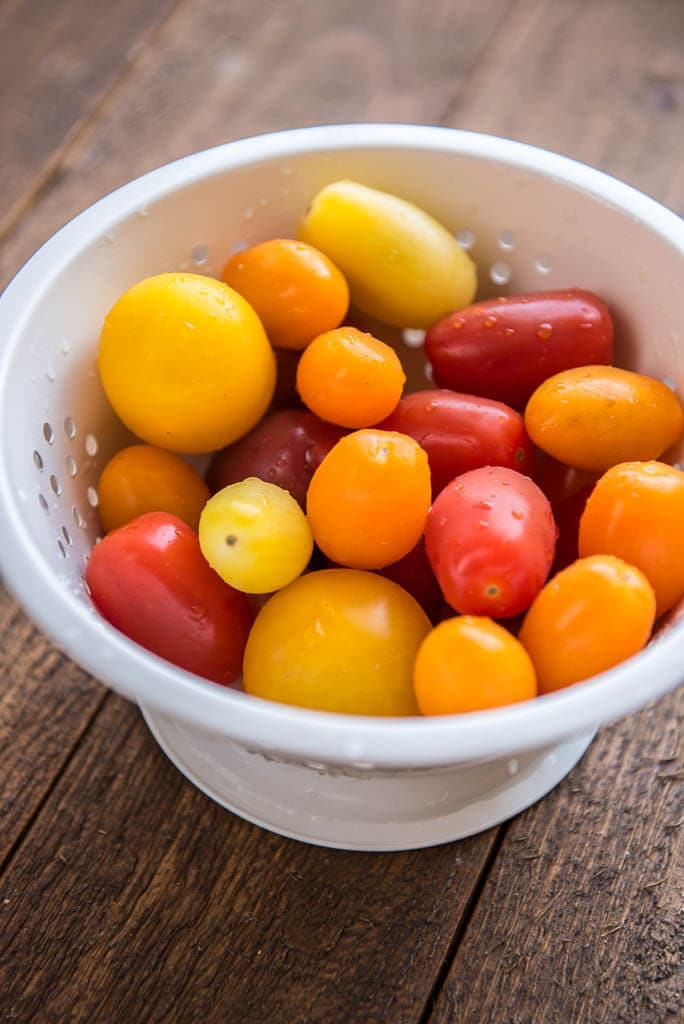 Red, orange and yellow baby tomatoes in a white colander for Wedge Salad with Herbed Buttermilk Dressing.