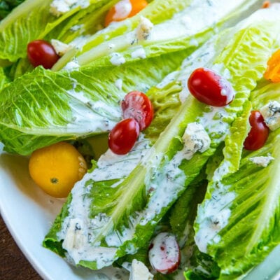 Romaine wedge salad with tomatoes and buttermilk dressing on a white platter.