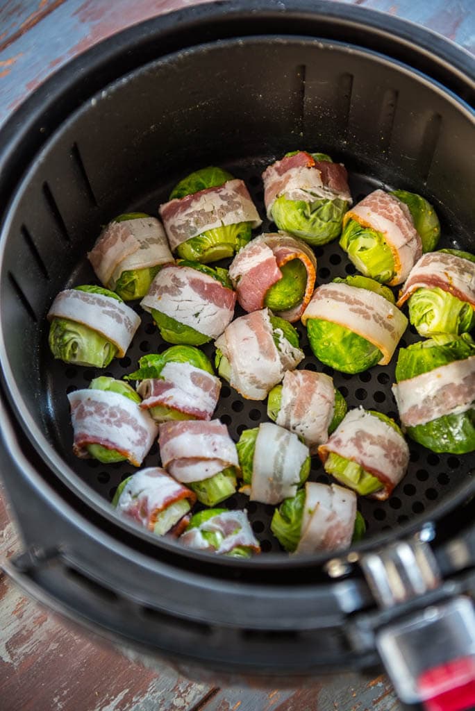 Raw veggies in the air fryer basket to make Air Fryer Bacon Wrapped Brussels sprouts