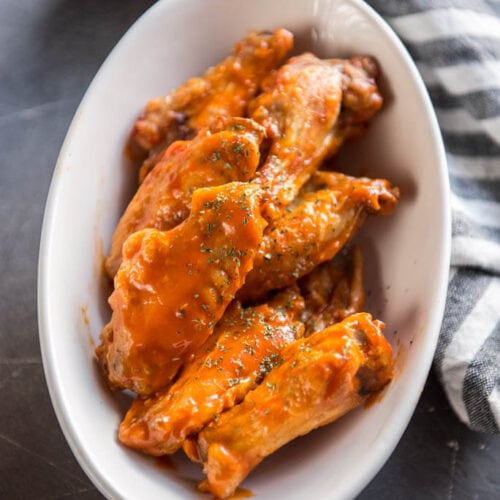 Air Fryer Chicken Wings tossed in buffalo sauce in white oval bowl