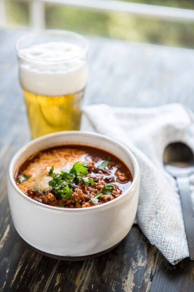 The Best IPA Beer Chili in a white bowl served with a frothy beer in a glass