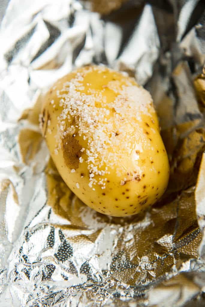 Yukon gold potato ready to bake topped with salt and sitting on foil