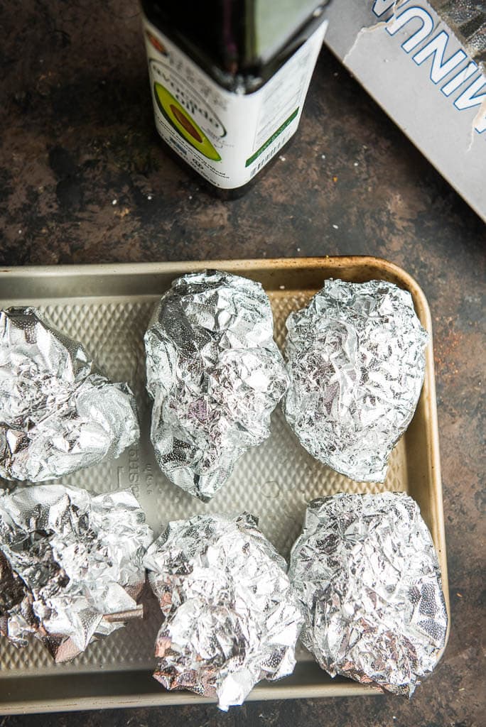 foil wrapped potatoes on a baking sheet ready to go on the grill