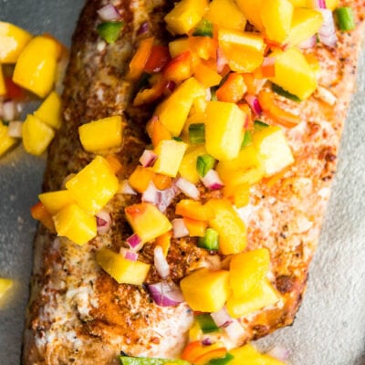 blackened smoked salmon topped with peach salsa on silver serving platter