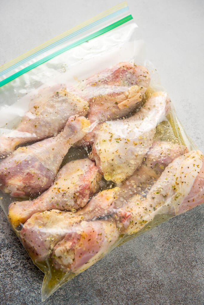 chicken drumsticks with lemon herb marinade in a plastic gallon zipper bag