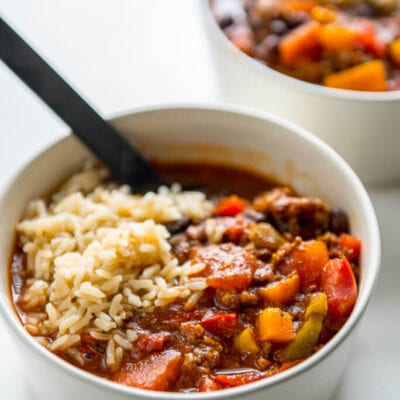 stuffed pepper soup in white bowl topped with brown rice