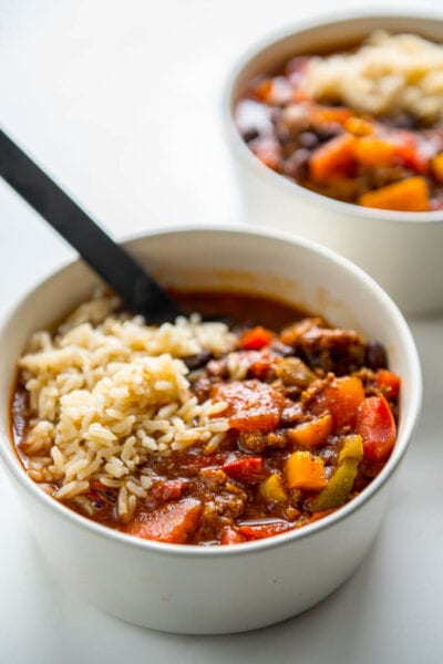 stuffed pepper soup in white bowl topped with brown rice