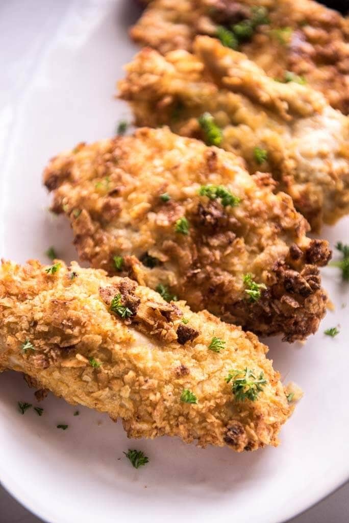 air fryer potato chip chicken on white platter sprinkled with fresh parsley 