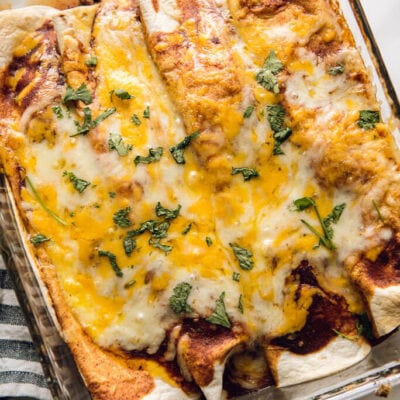 Easy Beef Enchiladas topped with melted cheese in glass casserole dish