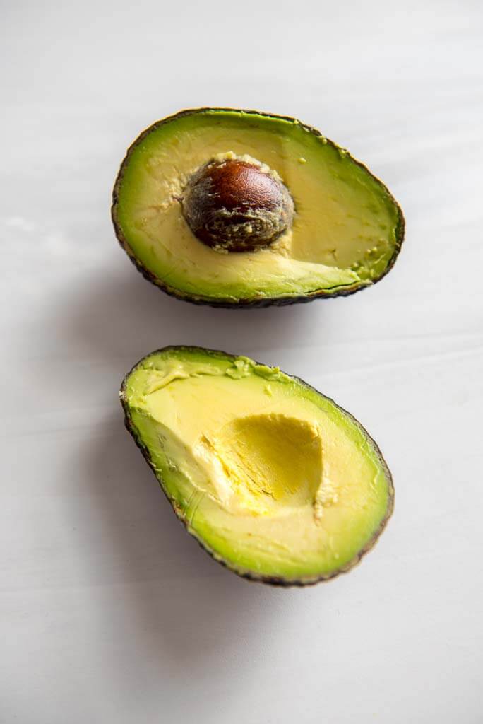 avocado cut in half on white countertop