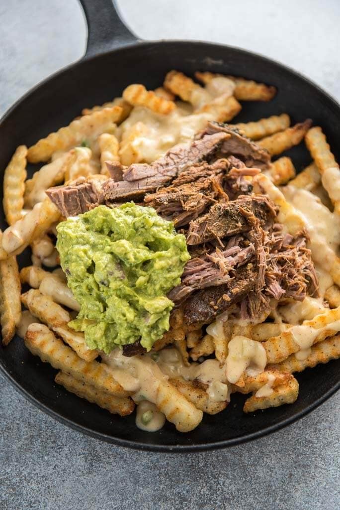 queso blanco dip on cheese fries with meat and guacamole