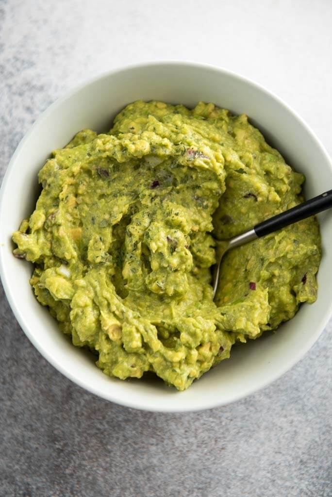 guacamole in a white bowl with a spoon