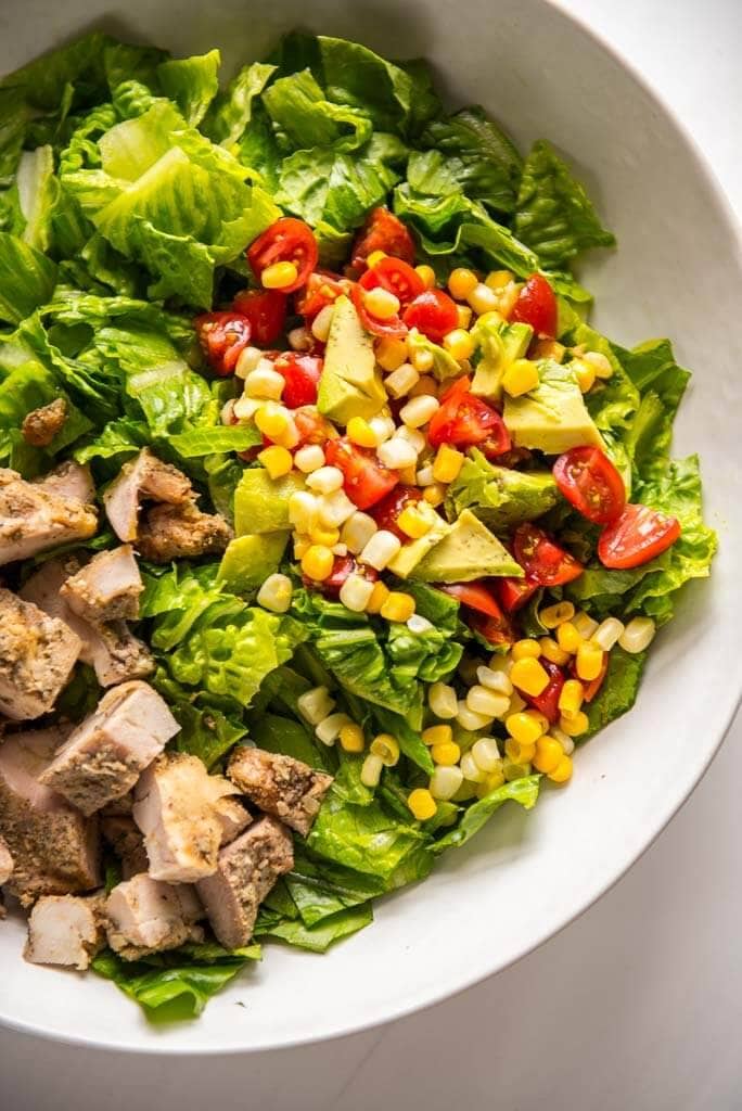 grilled chicken taco salad in white bowl with corn salsa