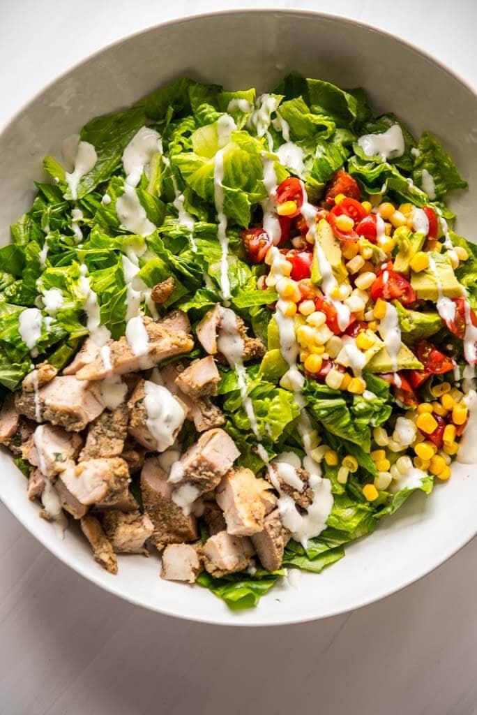 Grilled Chicken Taco Salad in white bowl with ranch dressing drizzle