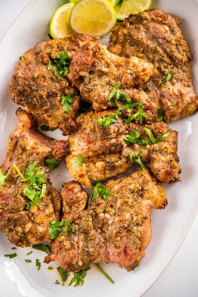 grilled chicken thighs topped with cilantro on a white platter