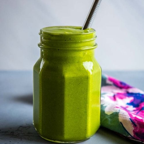 Mango Spinach Smoothie in glass mason jar with colorful napkin and metal straw