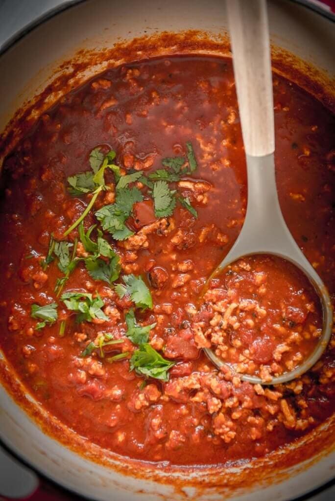 smoky chicken chili topped with cilantro in a red and white dutch oven