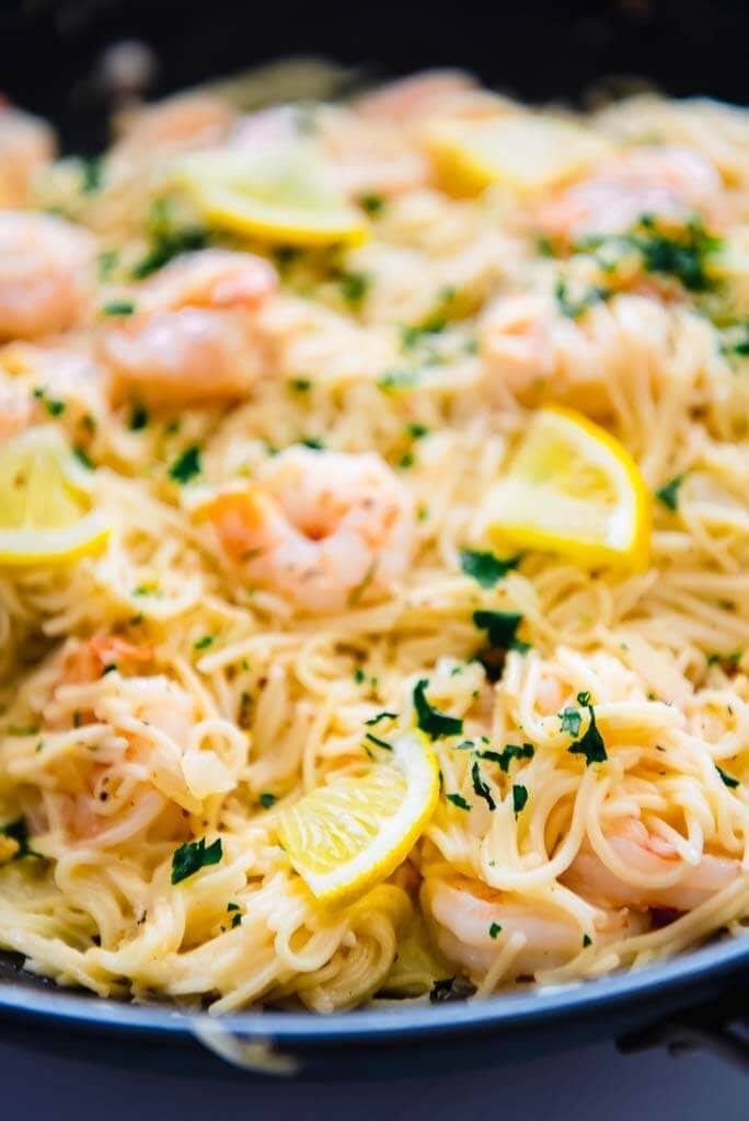 lemon garlic shrimp pasta in round skillet topped with lemon slices