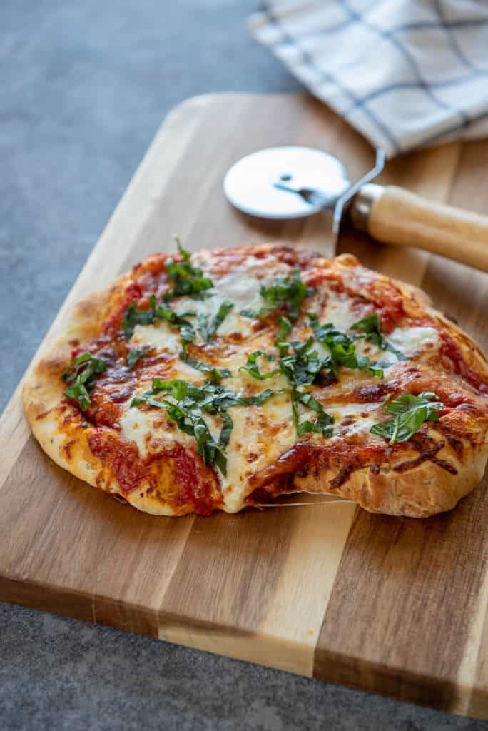 air fryer margherita pizza on cutting board with pizza cutter