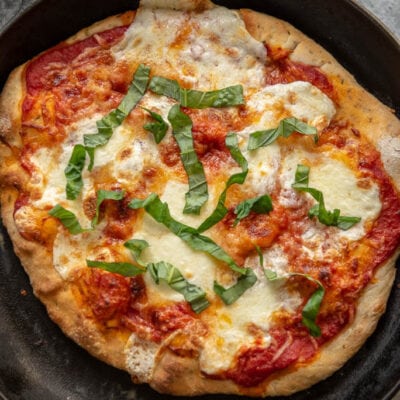 cast iron skillet with Margherita pizza topped with fresh basil