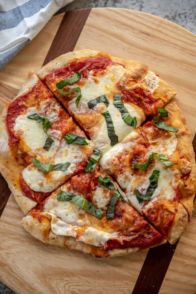 margherita pizza cut into 4 slices on round cutting board