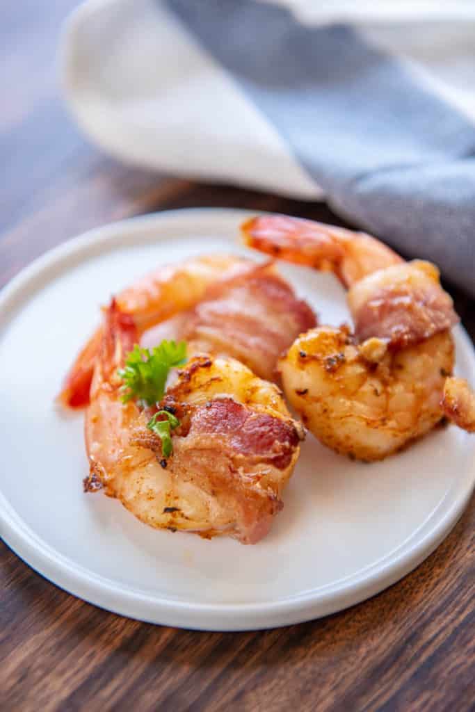 2 bacon wrapped shrimp from air fryer on white appetizer plate