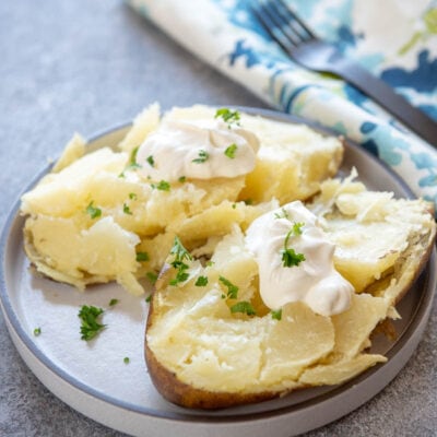 baked potato with sour cream and butter on white plate