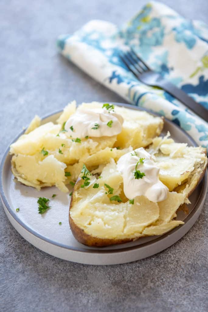 baked potato with sour cream and butter on white plate