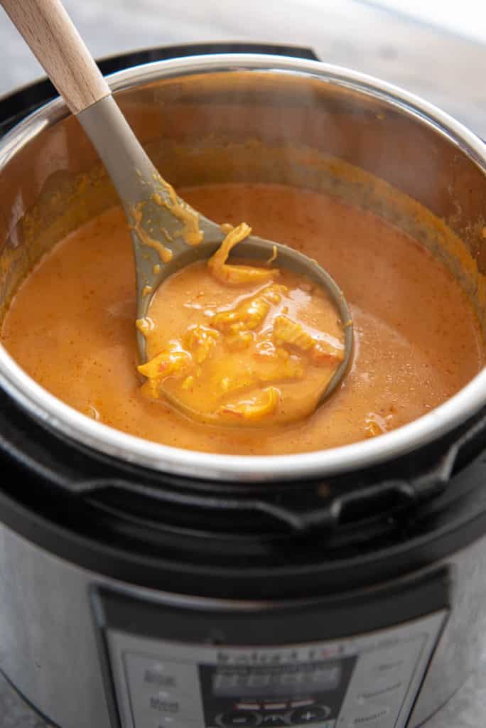 instant pot with ladle of butter chicken