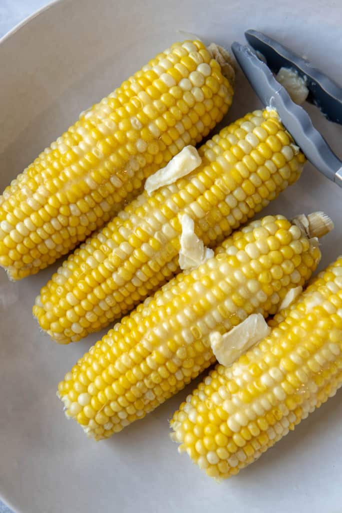 4 ears of cooked corn on the cob in a white bowl