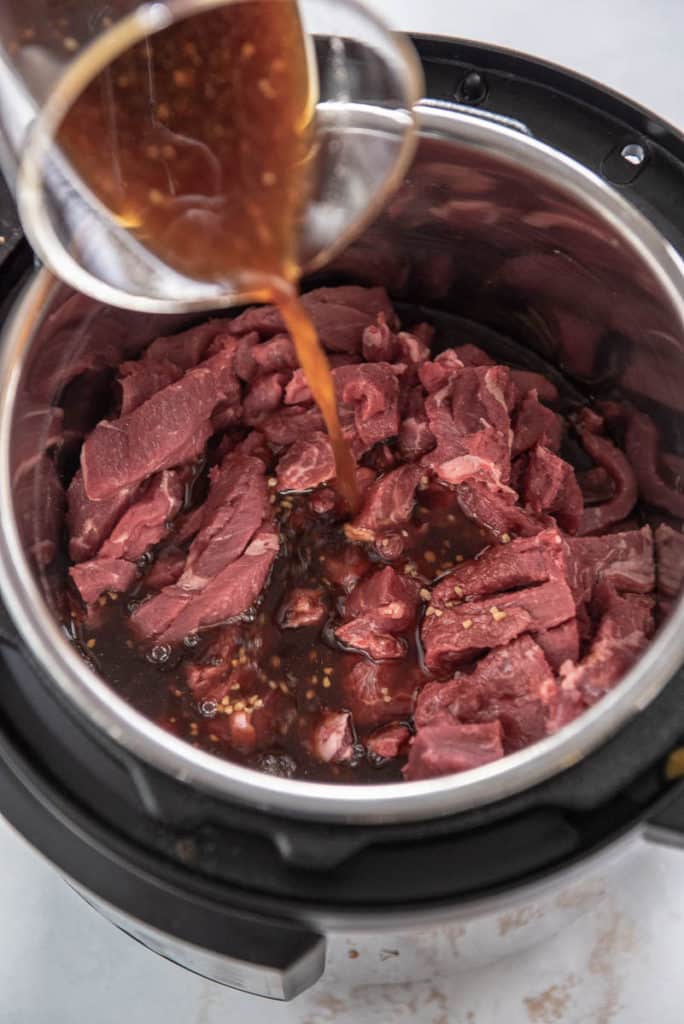 sauce being poured over beef in instant pot
