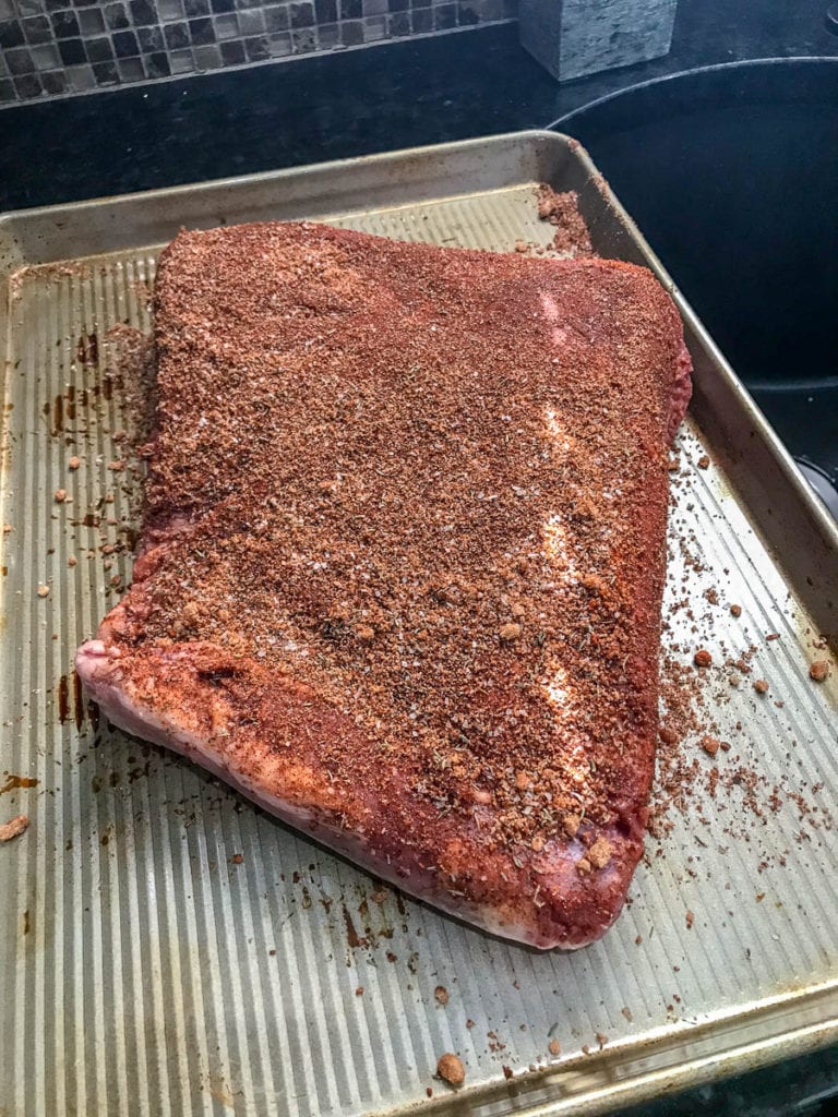 brisket with spice rub on cookie sheet