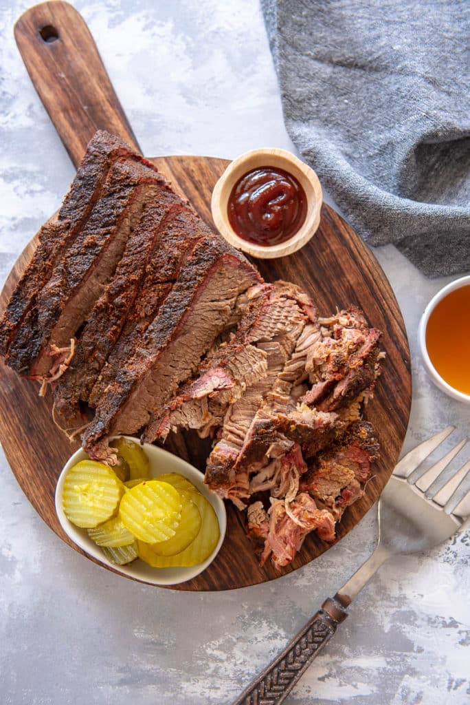 brisket with pickles and sauce on cutting board