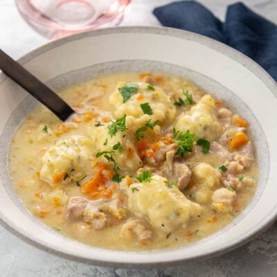 bowl of chicken and dumplings topped with fresh herbs