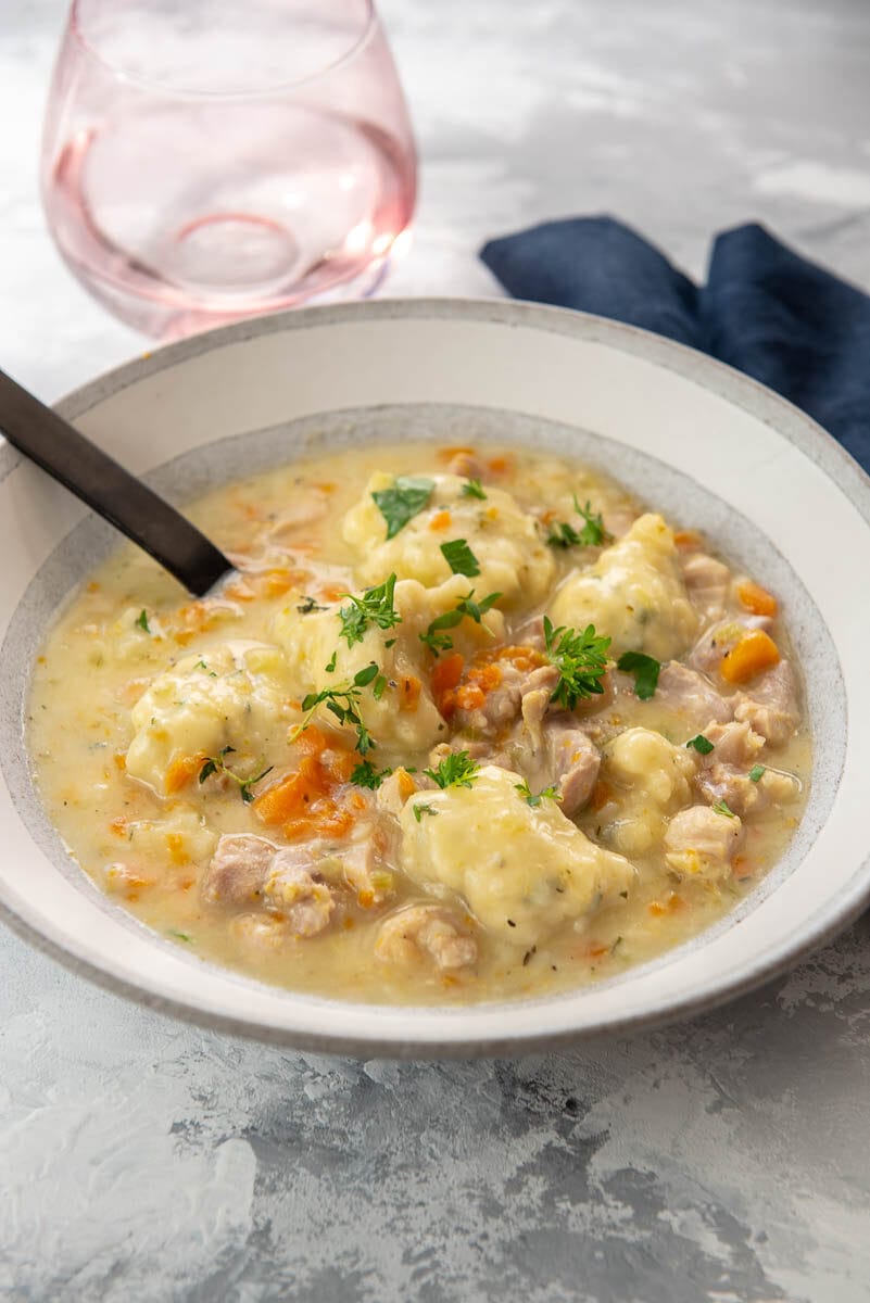 bowl of chicken and dumplings topped with fresh herbs