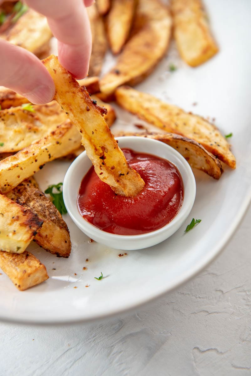 dipping an air fryer french fry into ketchup