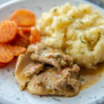 instant pot chicken thighs with gravy on plate with risotto and carrots