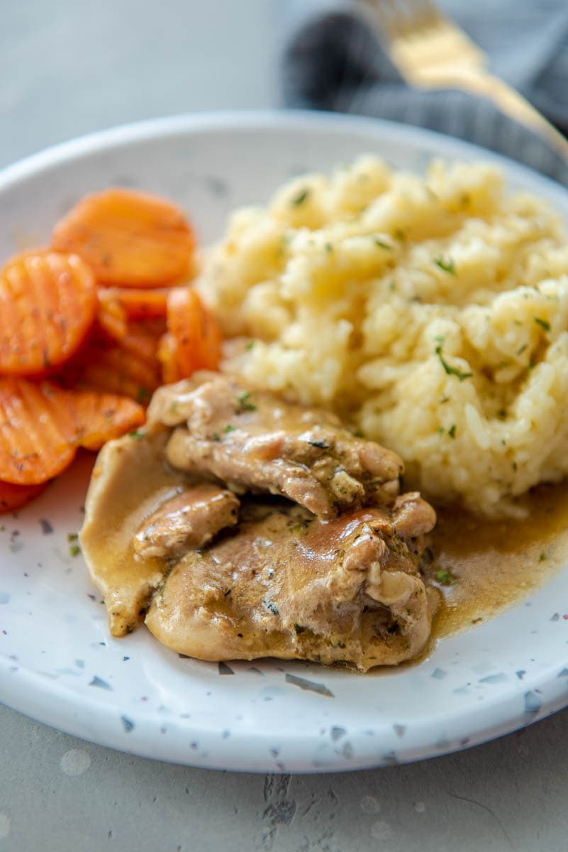 instant pot chicken thighs with gravy on plate with risotto and carrots