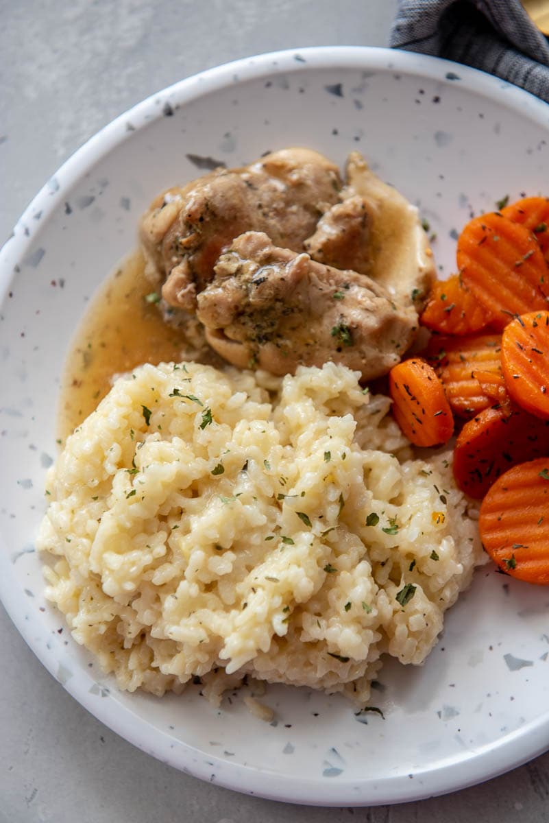 instant pot risotto on white plate next to chicken thighs and carrots