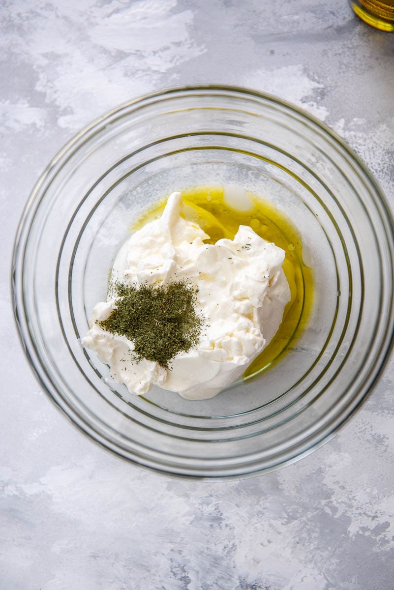 yogurt, olive oil and seasoning in glass bowl