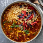 turkey tortilla soup in gray bowl topped with cheese and tri-color tortilla strips