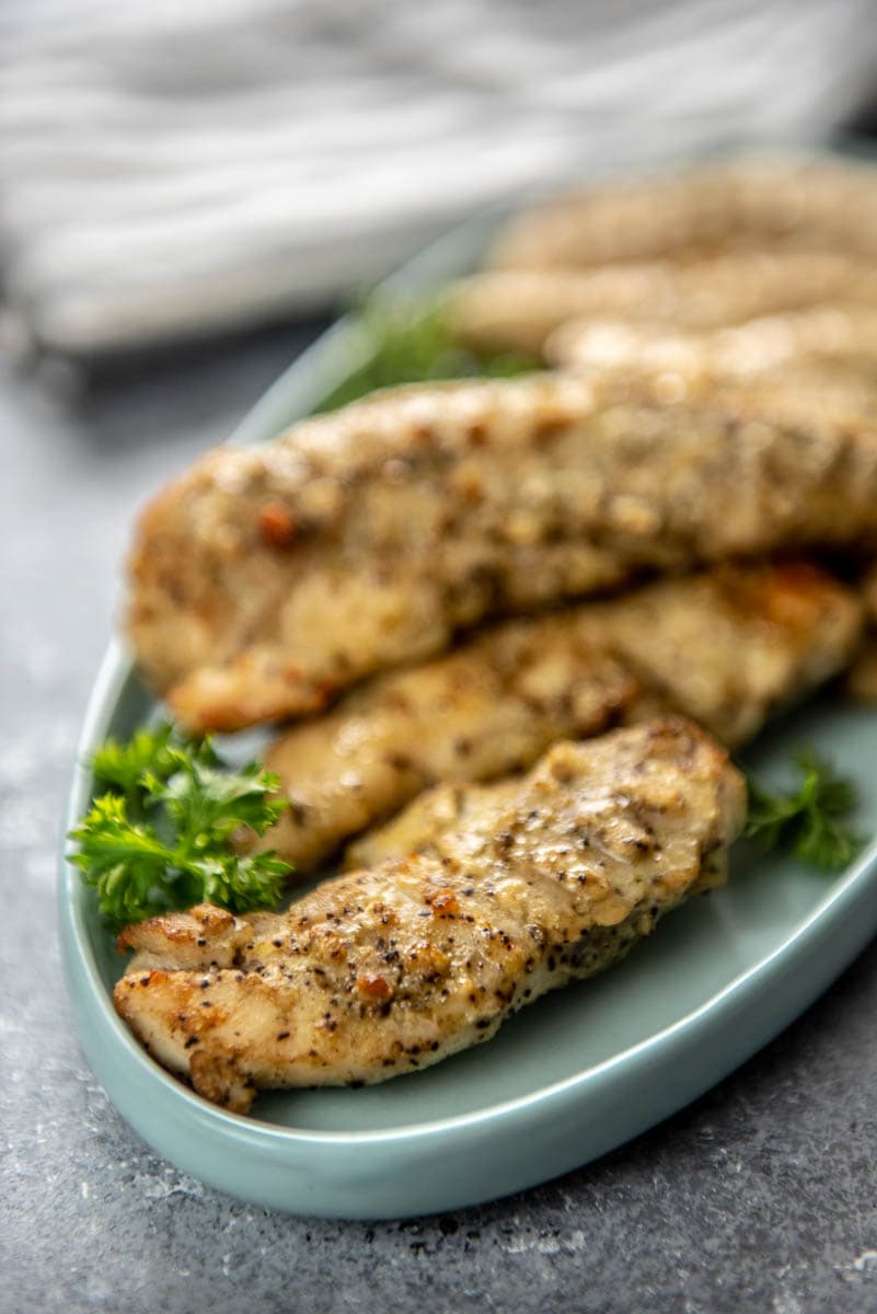 seasoned cooked chicken tenderloins on blue platter